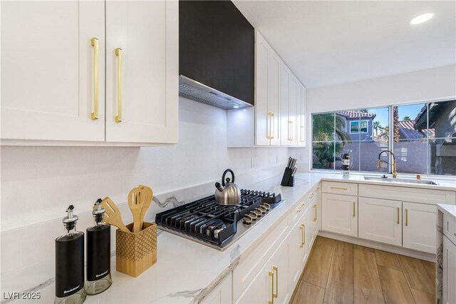 kitchen with stainless steel gas stovetop, light hardwood / wood-style flooring, white cabinets, and sink