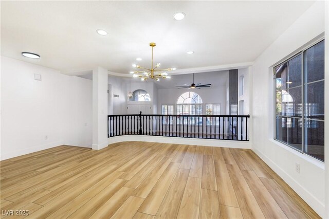 unfurnished room featuring ceiling fan with notable chandelier and light hardwood / wood-style floors