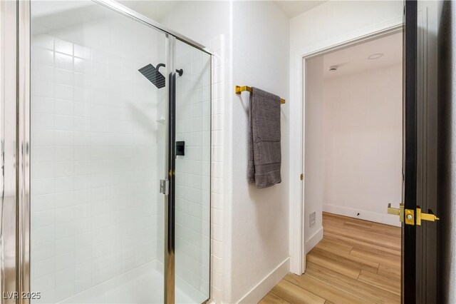 bathroom featuring a shower with shower door and hardwood / wood-style flooring