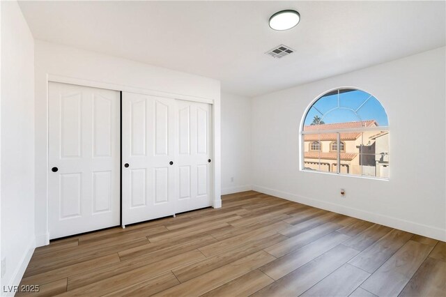 unfurnished bedroom with light wood-type flooring and a closet