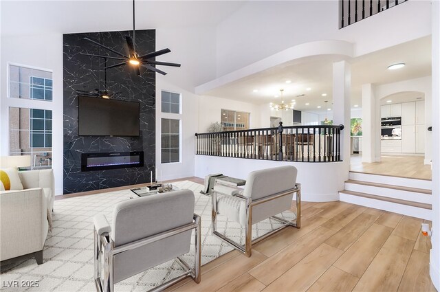 living room featuring a high end fireplace and ceiling fan with notable chandelier