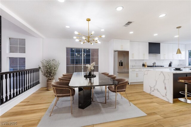 dining space featuring a chandelier, light hardwood / wood-style floors, and sink