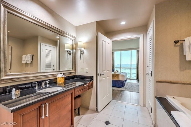 bathroom with tile patterned floors, tiled tub, and vanity