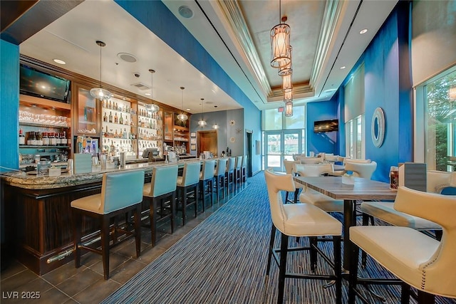 tiled dining area with crown molding, a tray ceiling, and bar area