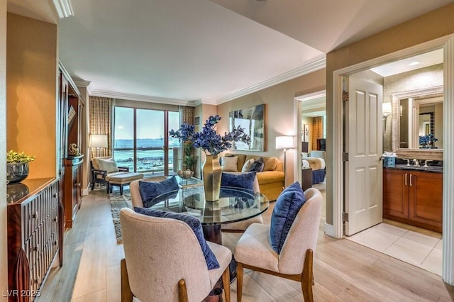 dining room featuring crown molding, light hardwood / wood-style floors, a water view, and sink