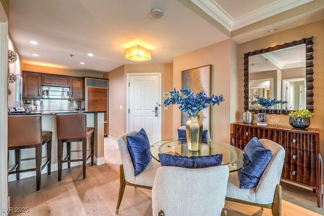 dining area with light wood-type flooring and ornamental molding