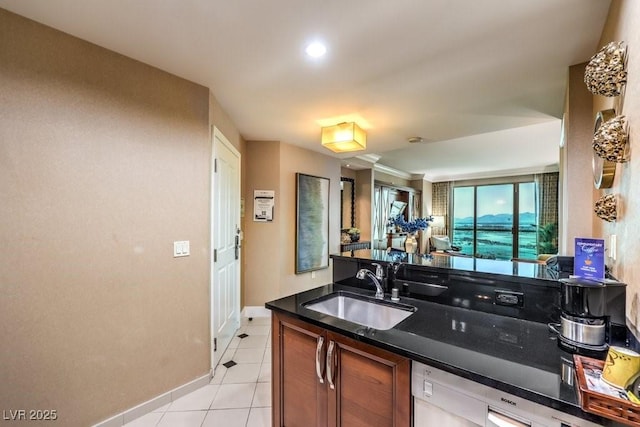 kitchen featuring sink, dishwashing machine, light tile patterned floors, and dark stone countertops