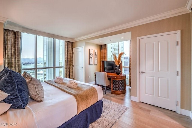 bedroom with light wood-type flooring, ornamental molding, a wall of windows, and multiple windows