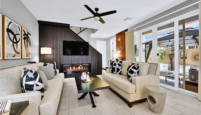 living room featuring ceiling fan and a fireplace