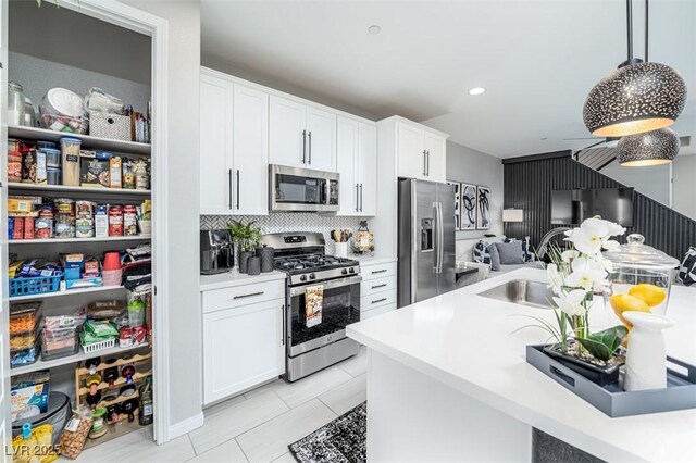 kitchen with light tile patterned floors, stainless steel appliances, pendant lighting, white cabinets, and sink