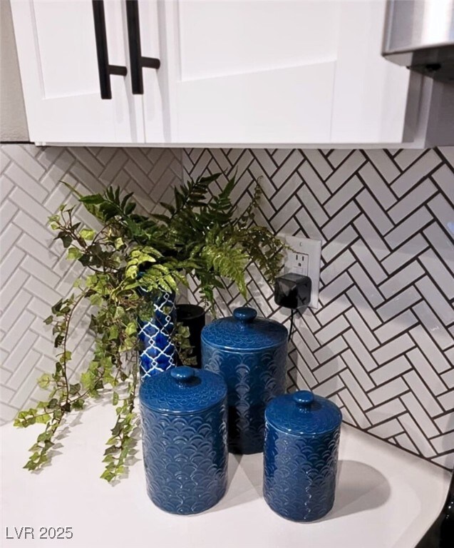 interior details featuring backsplash and white cabinetry