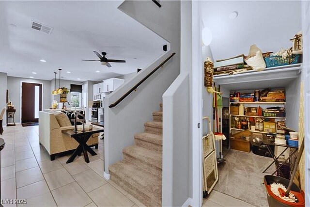 stairway with ceiling fan and tile patterned floors