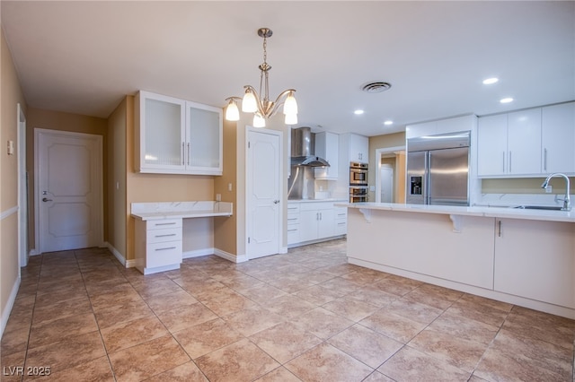 kitchen with wall chimney exhaust hood, sink, stainless steel appliances, and white cabinetry