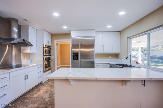 kitchen featuring a kitchen breakfast bar, wall chimney range hood, sink, and stainless steel appliances