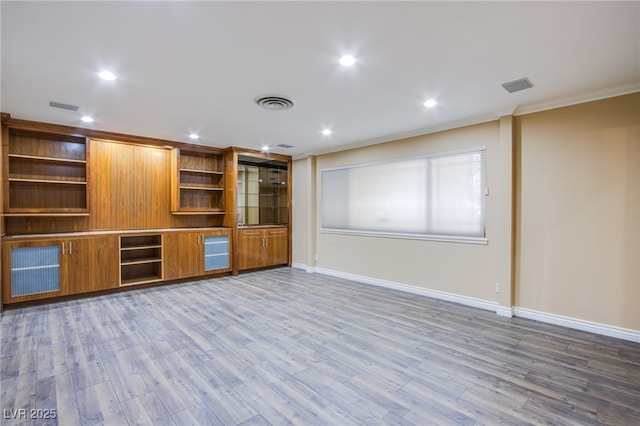 unfurnished living room featuring wood-type flooring and ornamental molding