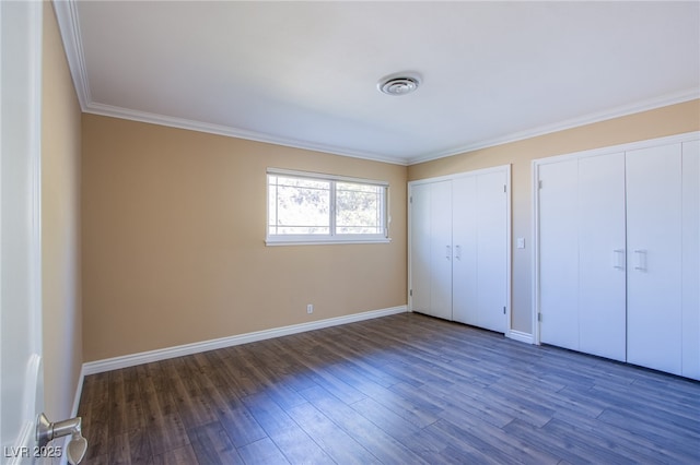 unfurnished bedroom featuring two closets, dark hardwood / wood-style flooring, and ornamental molding