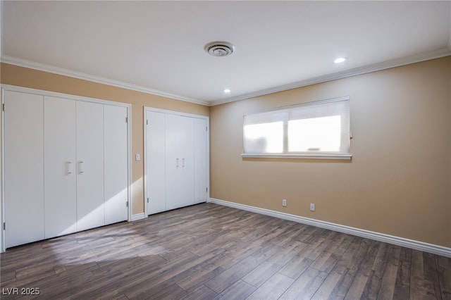 unfurnished bedroom featuring two closets, ornamental molding, and hardwood / wood-style flooring