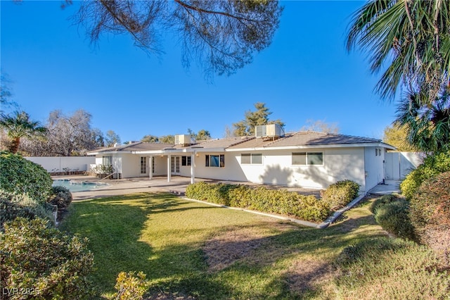 rear view of property with a patio area, a fenced in pool, a yard, and central AC unit