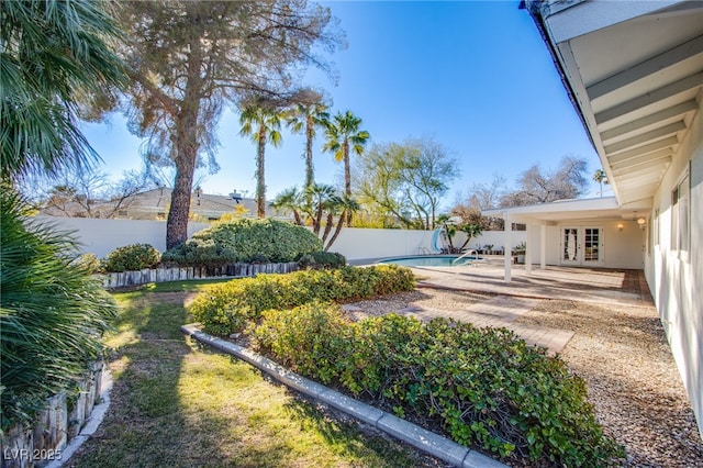 view of yard with french doors and a fenced in pool