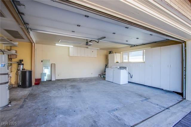 garage with a garage door opener, strapped water heater, and washing machine and clothes dryer