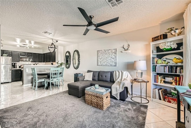 living room with ceiling fan, light tile patterned floors, and a textured ceiling