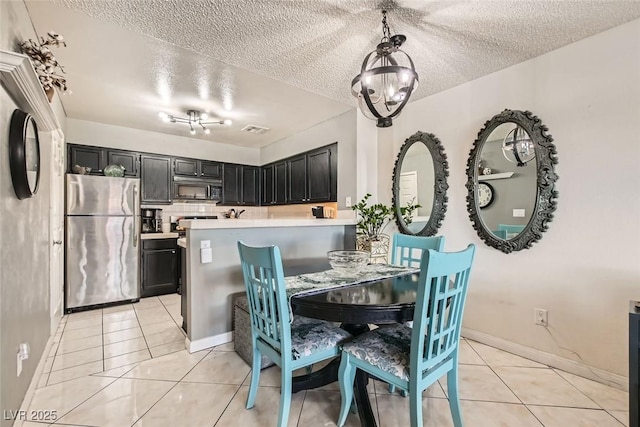 dining area with light tile patterned floors, a notable chandelier, and a textured ceiling