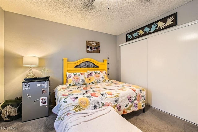 bedroom with ceiling fan, dark carpet, a closet, and a textured ceiling