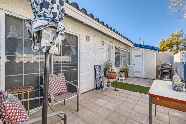 view of patio with a storage shed and a grill