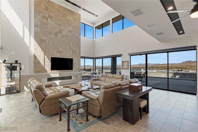 tiled living room with ceiling fan, a healthy amount of sunlight, and a towering ceiling