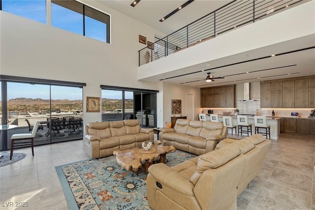 tiled living room with ceiling fan, a mountain view, and a towering ceiling