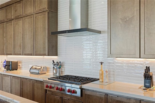 kitchen with tasteful backsplash, light countertops, stainless steel gas cooktop, and wall chimney range hood