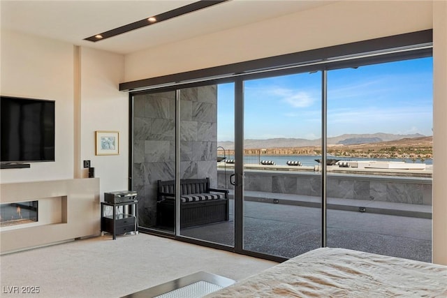 bedroom featuring light carpet, a tiled fireplace, and a water and mountain view