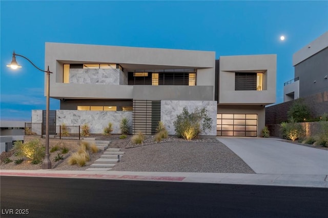 contemporary house featuring an attached garage, concrete driveway, stone siding, stairway, and stucco siding