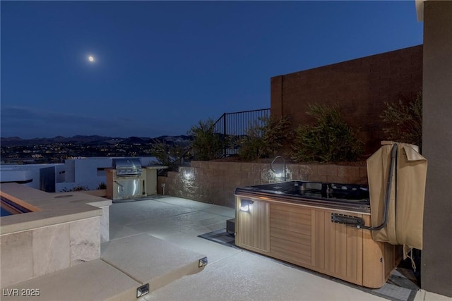 patio at night with grilling area and a hot tub