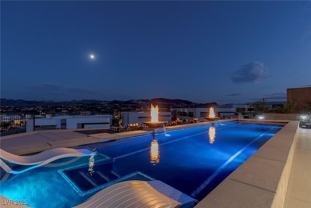 pool at night with an outdoor fire pit and a water slide