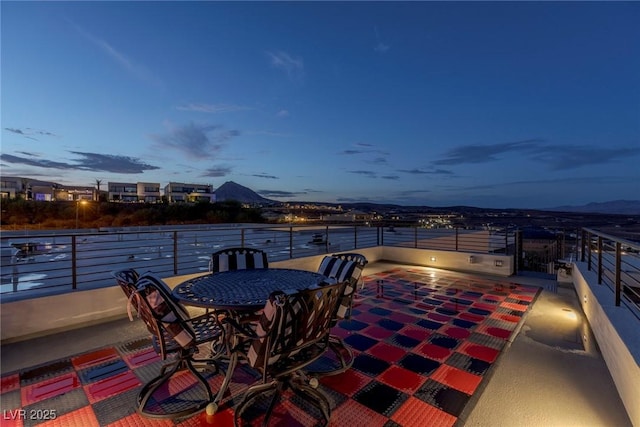 patio terrace at dusk with a mountain view and a balcony