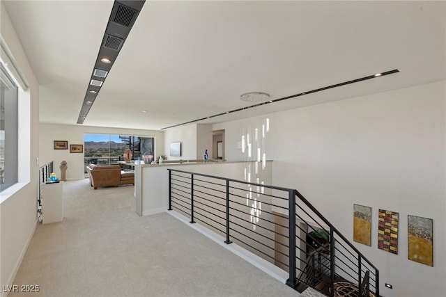 hall with baseboards, light colored carpet, and an upstairs landing