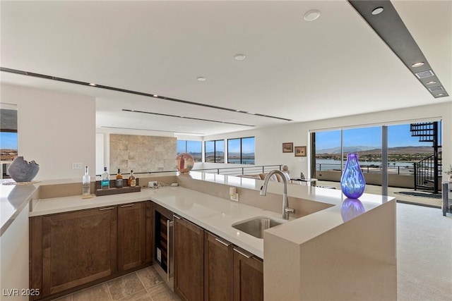 kitchen featuring kitchen peninsula, sink, beverage cooler, and light tile patterned flooring