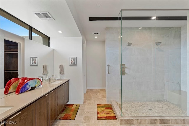 bathroom with double vanity, a shower stall, visible vents, and baseboards