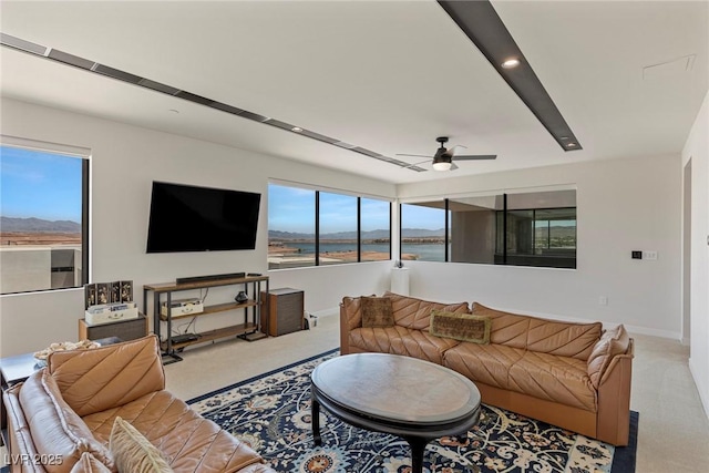 living area with baseboards, a ceiling fan, and light colored carpet