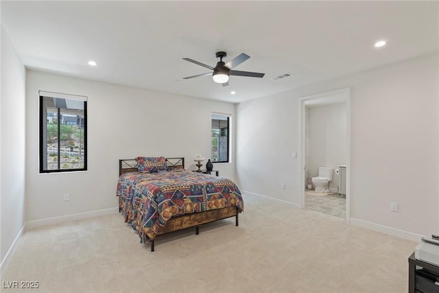 bedroom with ceiling fan, ensuite bathroom, and light carpet