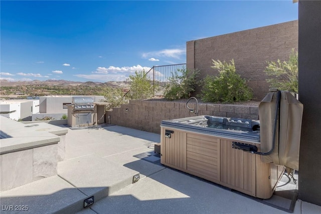 view of patio / terrace with fence, a mountain view, and a hot tub