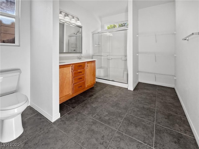 bathroom featuring toilet, vanity, and a shower with door