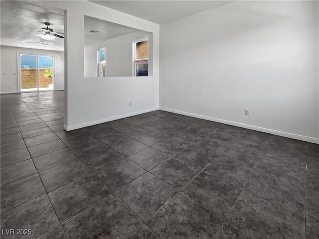 spare room with ceiling fan and dark tile patterned floors