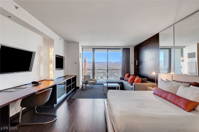 bedroom featuring a wall of windows and dark hardwood / wood-style flooring