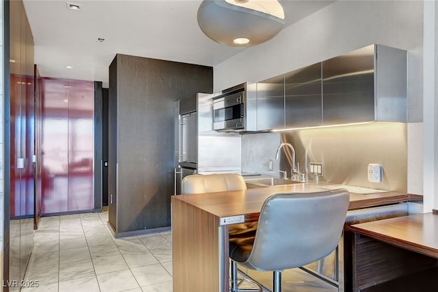 kitchen with stainless steel counters, sink, kitchen peninsula, and a kitchen breakfast bar