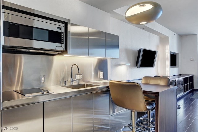 kitchen featuring black electric stovetop, dark hardwood / wood-style floors, tasteful backsplash, a breakfast bar, and sink