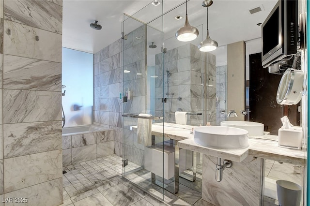 bathroom with an enclosed shower, tile walls, and dual sinks