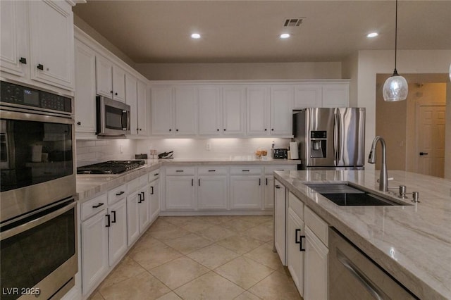 kitchen featuring light stone countertops, pendant lighting, appliances with stainless steel finishes, white cabinetry, and sink