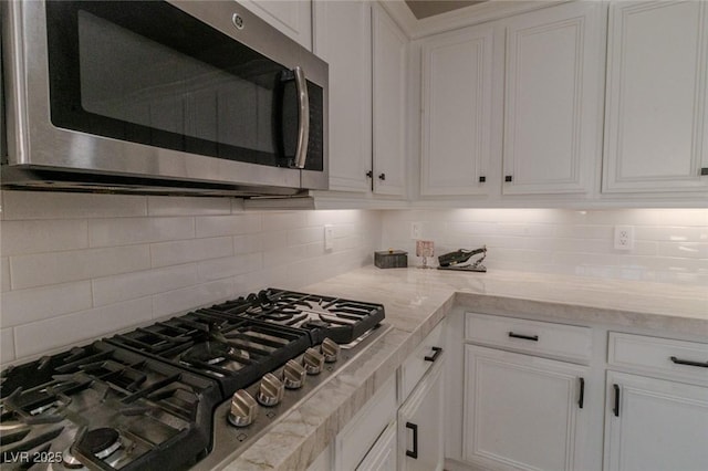 kitchen with light stone counters, white cabinets, appliances with stainless steel finishes, and tasteful backsplash